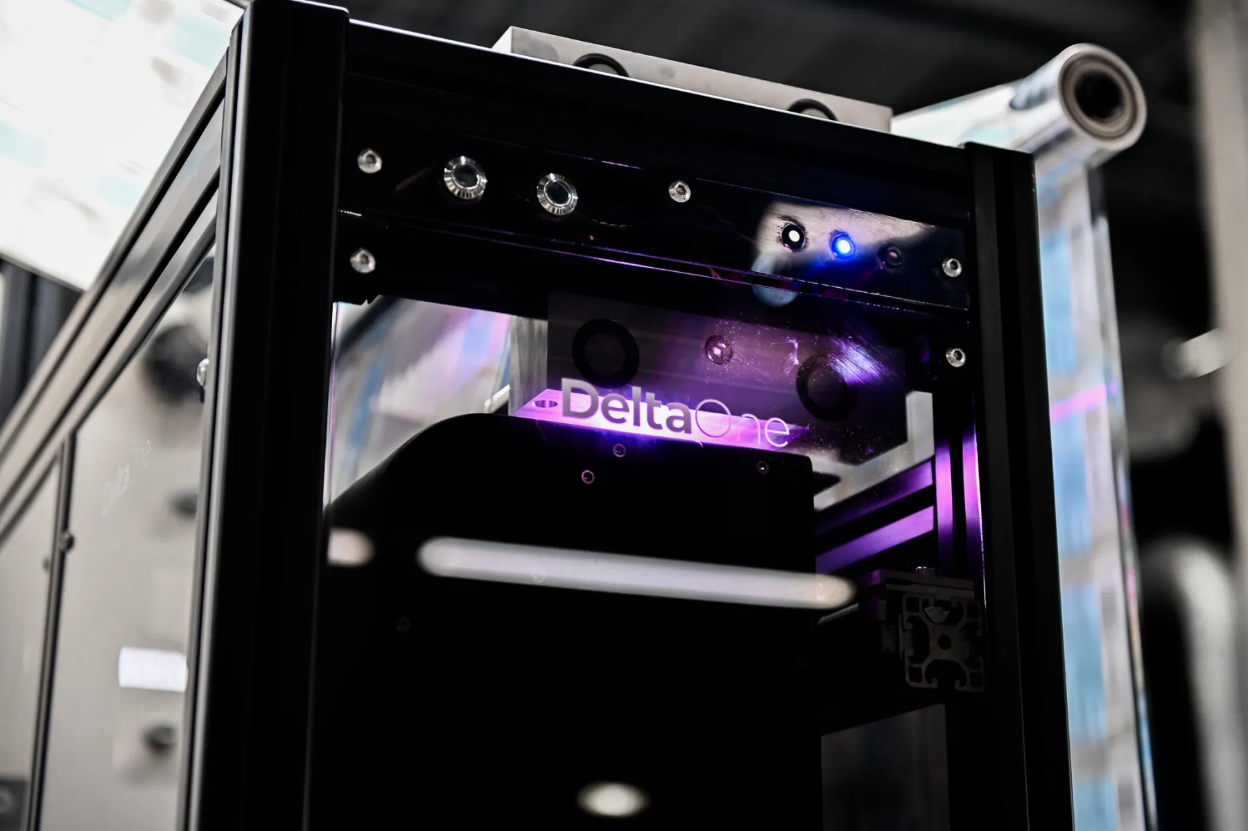 The DeltaOne inline scanner by Veoria on a label press, lit in violet